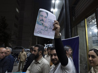 A supporter of Masoud Pezeshkian, an Iranian reformist presidential candidate, is holding up a portrait of former Iranian reformist Presiden...