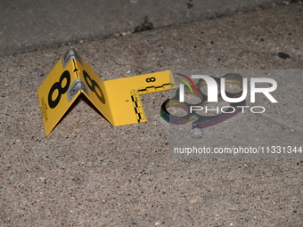 An evidence marker is highlighting evidence found at the crime scene. An unidentified male is being wounded after being shot while standing...