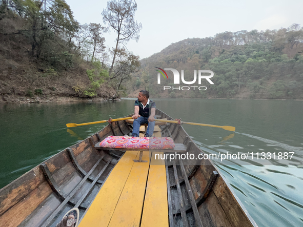 A boatman is rowing a boat along Sattal Lake in Sattal (Sat Tal), Uttarakhand, India, on April 20, 2024. 