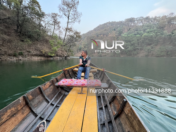 A boatman is rowing a boat along Sattal Lake in Sattal (Sat Tal), Uttarakhand, India, on April 20, 2024. 