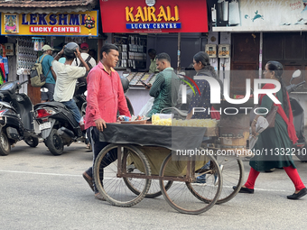 A man is pushing a cart along in the East Fort area as he sells roasted peanuts and popcorn in Thiruvananthapuram (Trivandrum), Kerala, Indi...