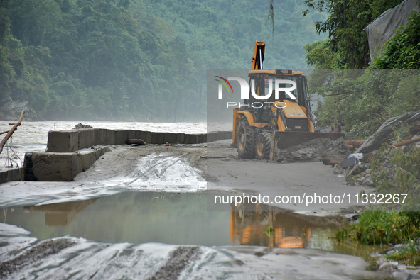 An excavator is clearing the debris and rocks on the road of Teesta River, which flows beside National Highway 10, connecting the neighborin...