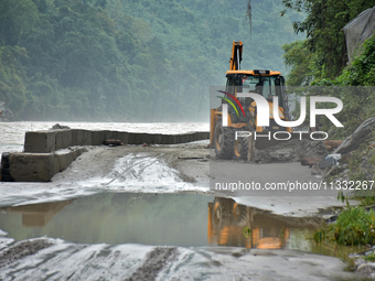 An excavator is clearing the debris and rocks on the road of Teesta River, which flows beside National Highway 10, connecting the neighborin...