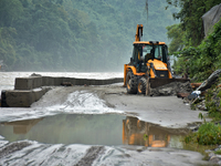 An excavator is clearing the debris and rocks on the road of Teesta River, which flows beside National Highway 10, connecting the neighborin...