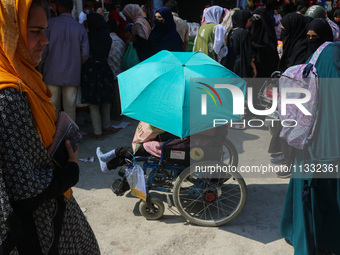 A woman in a wheelchair is holding an umbrella as she shops at a market ahead of the Eid al-Adha festival in Srinagar, India, on June 15, 20...