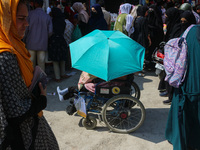 A woman in a wheelchair is holding an umbrella as she shops at a market ahead of the Eid al-Adha festival in Srinagar, India, on June 15, 20...