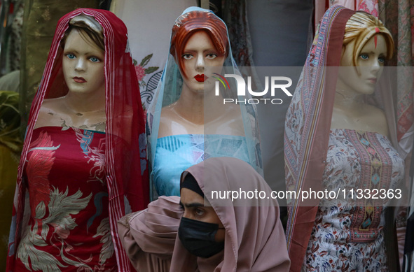 A girl is walking past mannequins that are decorated at a market ahead of the Eid al-Adha festival in Srinagar, India, on June 15, 2024. Eid...