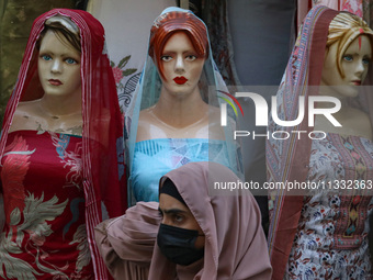 A girl is walking past mannequins that are decorated at a market ahead of the Eid al-Adha festival in Srinagar, India, on June 15, 2024. Eid...