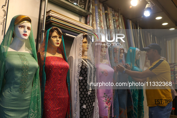 A man is adjusting a mannequin at a market ahead of the Eid al-Adha festival in Srinagar, India, on June 15, 2024. Eid al-Adha is the holies...