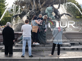 People are enjoying their time at Neptune Fountain in Berlin, Germany, on June 15, 2024. (