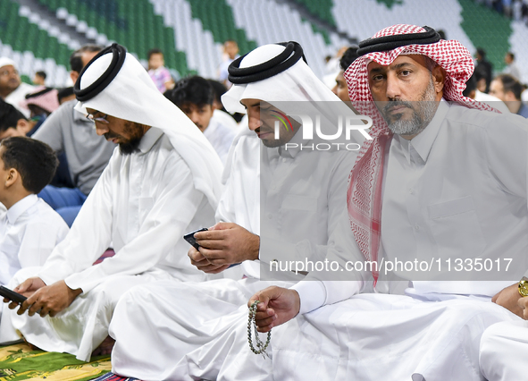 Muslim men are sitting before performing Eid al-Adha morning prayers at the Education City Stadium in Doha, Qatar, on June 16, 2024. Muslims...