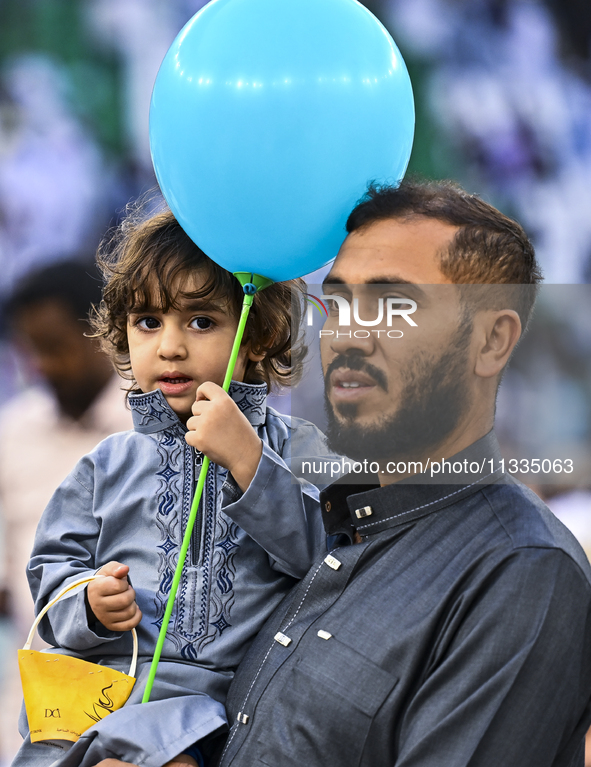 A boy is celebrating with a balloon after performing the Eid al-Adha morning prayer at the Education City Stadium on the first day of the Ei...