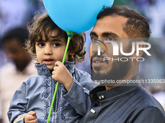 A boy is celebrating with a balloon after performing the Eid al-Adha morning prayer at the Education City Stadium on the first day of the Ei...