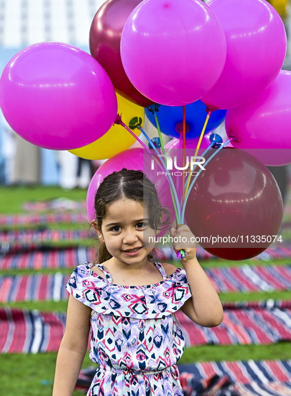 A girl is celebrating with balloons after performing the Eid al-Adha morning prayer at the Education City Stadium on the first day of the Ei...