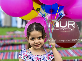 A girl is celebrating with balloons after performing the Eid al-Adha morning prayer at the Education City Stadium on the first day of the Ei...