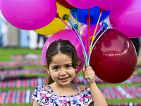 A girl is celebrating with balloons after performing the Eid al-Adha morning prayer at the Education City Stadium on the first day of the Ei...