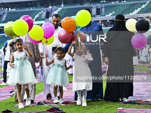 A girl is celebrating with balloons after performing the Eid al-Adha morning prayer at the Education City Stadium on the first day of the Ei...