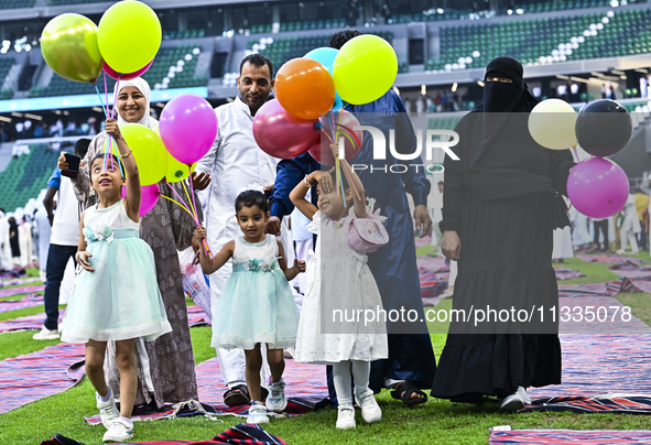 A girl is celebrating with balloons after performing the Eid al-Adha morning prayer at the Education City Stadium on the first day of the Ei...