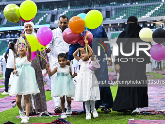 A girl is celebrating with balloons after performing the Eid al-Adha morning prayer at the Education City Stadium on the first day of the Ei...