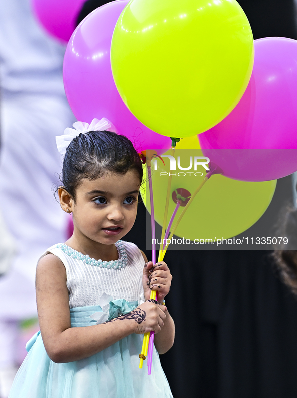 A girl is celebrating with balloons after performing the Eid al-Adha morning prayer at the Education City Stadium on the first day of the Ei...