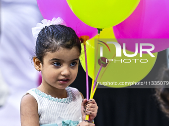 A girl is celebrating with balloons after performing the Eid al-Adha morning prayer at the Education City Stadium on the first day of the Ei...