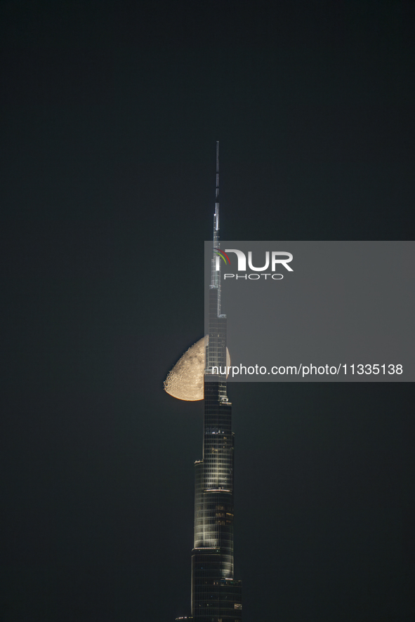 The Moon is appearing behind the world's tallest tower, Burj Khalifa, in Dubai, UAE, on June 16, 2024. 