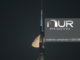 The Moon is appearing behind the world's tallest tower, Burj Khalifa, in Dubai, UAE, on June 16, 2024. (