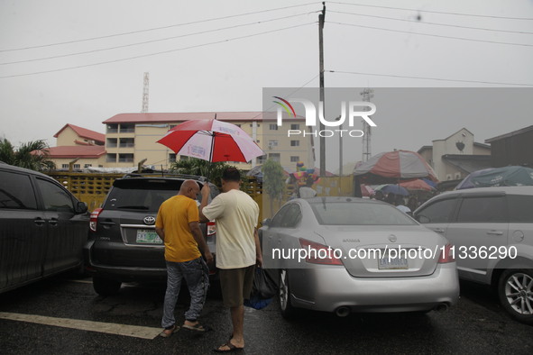 Chinese men are holding an umbrella as they are leaving Sunday Market in Ogba, Ikeja, while the Muslim faithful are praying to mark the Eid-...