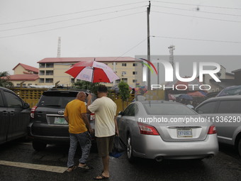 Chinese men are holding an umbrella as they are leaving Sunday Market in Ogba, Ikeja, while the Muslim faithful are praying to mark the Eid-...