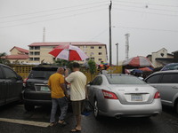 Chinese men are holding an umbrella as they are leaving Sunday Market in Ogba, Ikeja, while the Muslim faithful are praying to mark the Eid-...