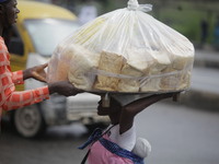 A man who is wanting to buy bread is helping a vendor drop a load of loaves off her head as Muslim faithful are praying to mark the Eid-El-K...