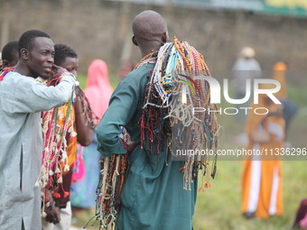 Prayer beads sellers are chatting as Muslim faithful are praying to mark the Eid-El-Kabir festival in Ikeja, Lagos, Nigeria, on Sunday, June...