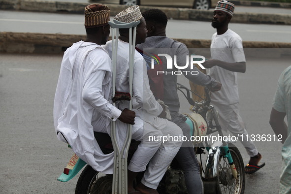 A commercial motorcyclist is carrying passengers as Muslim faithful are praying to mark the Eid-El-Kabir festival in Ikeja, Lagos, Nigeria,...