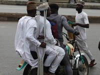 A commercial motorcyclist is carrying passengers as Muslim faithful are praying to mark the Eid-El-Kabir festival in Ikeja, Lagos, Nigeria,...