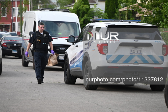 An evidence bag is being loaded into a Chicago police vehicle at the crime scene. Two people are being shot, with one person being shot mult...