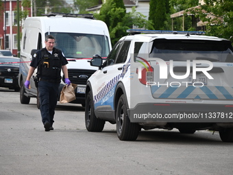 An evidence bag is being loaded into a Chicago police vehicle at the crime scene. Two people are being shot, with one person being shot mult...