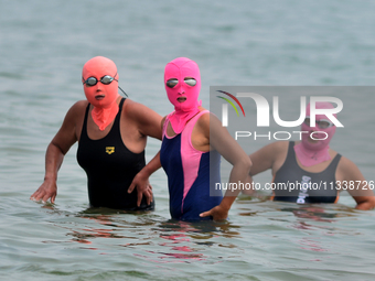 Three people are wearing face-kinis to cool off in the water at the No. 1 Bathing Beach in Qingdao, China, on June 17, 2024. (