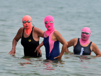 Three people are wearing face-kinis to cool off in the water at the No. 1 Bathing Beach in Qingdao, China, on June 17, 2024. (