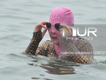 A citizen is wearing a face-kini with sun protection and cooling off in the water at the No. 1 Bathing Beach in Qingdao, China, on June 17,...