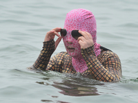 A citizen is wearing a face-kini with sun protection and cooling off in the water at the No. 1 Bathing Beach in Qingdao, China, on June 17,...