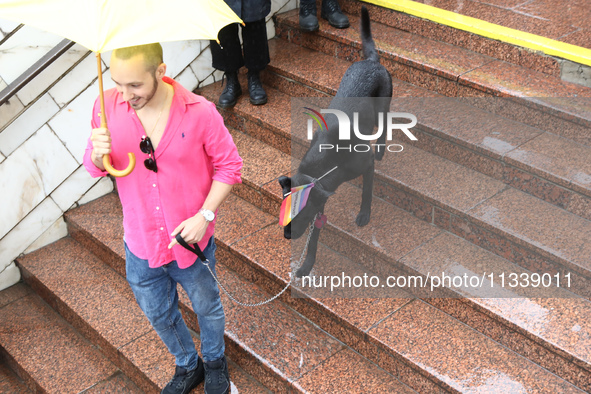 A man with a dog is going down the steps to an underground passage as he shields himself from the rain with an umbrella during the Equality...