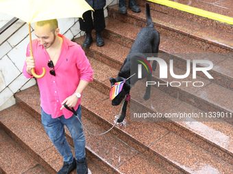 A man with a dog is going down the steps to an underground passage as he shields himself from the rain with an umbrella during the Equality...