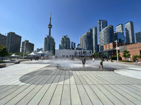 People are cooling off during a hot summer afternoon as they walk amongst water vapor being sprayed from the ground in Toronto, Ontario, Can...