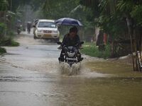 A man is riding his bike through a flooded road following rains in Changchaki village in Nagaon District of Assam, India, on June 18, 2024....