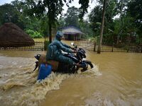 A man is riding his bike through a flooded road following rains in Changchaki village in Nagaon District of Assam, India, on June 18, 2024....