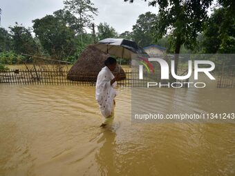 A woman is walking through a flooded road following rains in Changchaki village in Nagaon District of Assam, India, on June 18, 2024. (