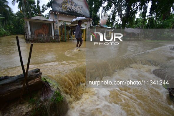 A man is walking through a flooded road following rains in Changchaki village in Nagaon District of Assam, India, on June 18, 2024. 