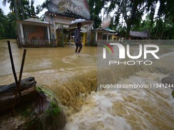 A man is walking through a flooded road following rains in Changchaki village in Nagaon District of Assam, India, on June 18, 2024. (