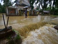 A man is walking through a flooded road following rains in Changchaki village in Nagaon District of Assam, India, on June 18, 2024. (