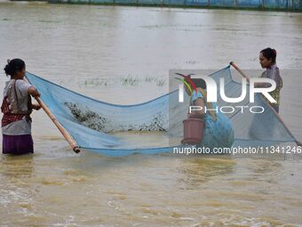 People are fishing on flood water following rains in Changchaki village in Nagaon District of Assam, India, on June 18, 2024. (